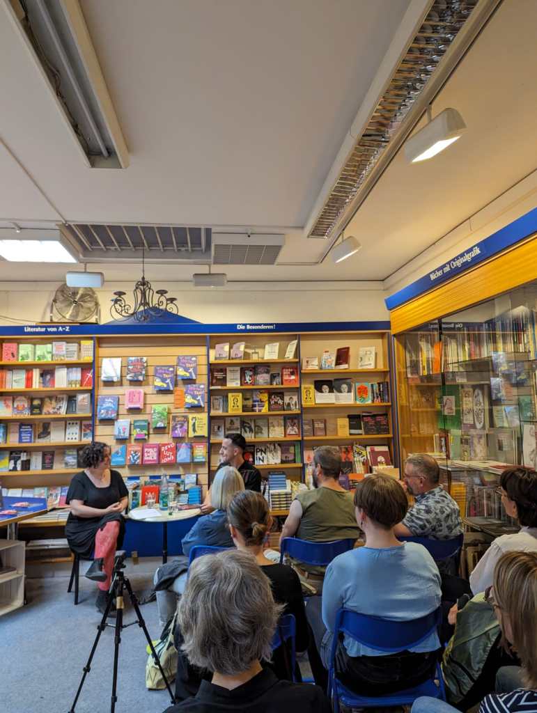 E.G. Condé and Lisa Stöhr converse in front of a crowd gathered in Frankfurt for a book event at Buchergilde Buchandlung